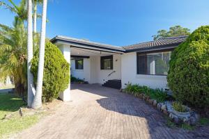 a white house with palm trees and a driveway at Spacious House with Pool - 5 min walk to Lake in Wyong