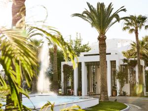 uma casa branca com palmeiras e uma fonte em Grecotel Creta Palace em Rethymno Town