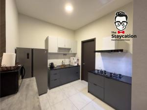 una cocina con armarios negros y un cartel en la pared en Staycation Homestay 41 Liberty Grove Near Airport en Kuching