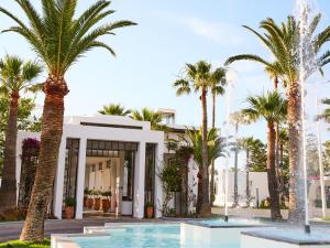 een gebouw met palmbomen en een zwembad bij Grecotel Creta Palace in Rethimnon