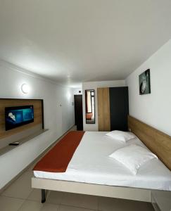 a bedroom with a large bed and a flat screen tv at Hotel Recif in Neptun
