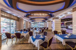 a dining room with tables and chairs and a chandelier at Tac Premier Hotel & Spa in Alanya