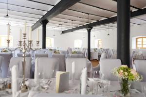 una habitación llena de mesas y sillas blancas con mesas blancas y sillas blancas en Hotel Stanglbräu 