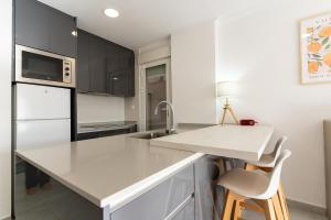 eine Küche mit weißen Schränken und einer weißen Arbeitsplatte in der Unterkunft rentafive Apartamento del Mar Piscina Vistas in Santa Pola