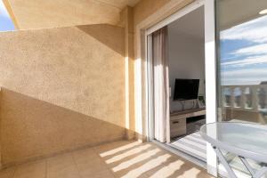 d'un balcon avec une porte coulissante en verre et une télévision. dans l'établissement rentafive Apartamento del Mar Piscina Vistas, à Santa Pola
