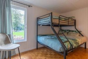 a bunk bed in a room with a chair and a window at 2 bedrooms chalet with enclosed garden and wifi at Merksplas Merksplas 