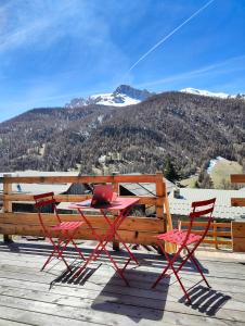 a table and chairs on a deck with a laptop at Chambre d'hôtes Chalet AILLEURS in Molines-en-Queyras