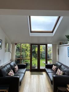 a living room with black leather furniture and a skylight at Peaceful Family Retreat Near Gloucester Road in Bristol