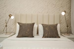 a white bed with two lamps and two pillows at Nasma Luxury Stays - Beachfront rental in Pacific Towers on Al Marjan Island in Ras al Khaimah
