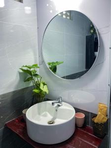 ein Badezimmer mit einem weißen Waschbecken und einem Spiegel in der Unterkunft Dorry Le's House in Gia Nghĩa