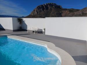 a swimming pool with a bench next to a white wall at Vista Segaria Apartment in El Vergel in El Verger