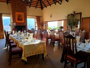 a dining room with tables and chairs with white tablecloths at Silver Hill Lodge in Kamberg Valley