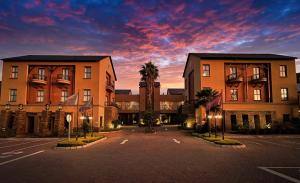 a parking lot in front of a building with palm trees at Royal Elephant Hotel & Conference Centre in Centurion