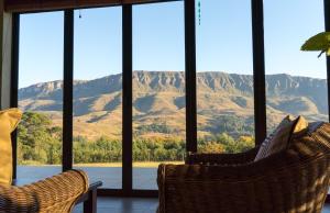 a room with two chairs and a view of mountains at Silver Hill Lodge in Kamberg Valley