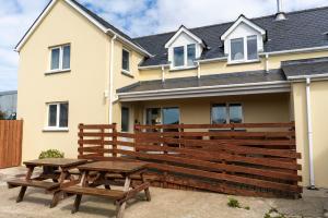 two picnic tables in front of a house at Cnwc Y Boidy Llangrannog in Llangranog