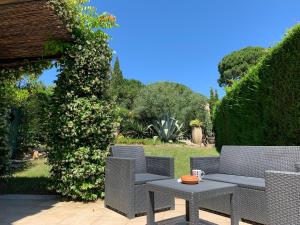 a patio with two chairs and a table and a bush at Maison spacieuse avec piscine partagée à Gassin in Gassin