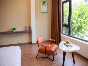 een kamer met een stoel, een tafel en een raam bij CENTRAL BOUTIQUE HOTEL in Da Nang