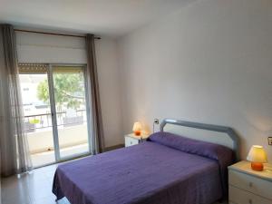 a bedroom with a purple bed and a large window at Adosado Peñismar II Orangecosta in Peniscola