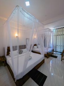 een slaapkamer met een hemelbed met witte klamboes bij Kai Kazee Ella in Ella