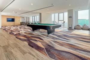 stół bilardowy w dużym pokoju z dywanem w obiekcie Frank Porter - 1 Residences West w Dubaju