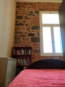 ein Schlafzimmer mit einer Ziegelwand, einem Bett und einem Fenster in der Unterkunft Νεοκλασική Κατοικία στο Κέντρο in Mytilini