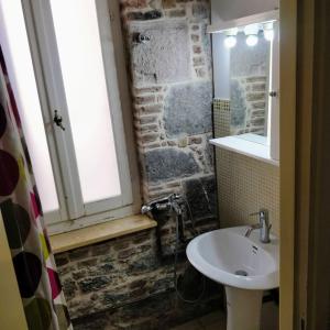 ein Badezimmer mit einem Waschbecken und einer Steinmauer in der Unterkunft Νεοκλασική Κατοικία στο Κέντρο in Mytilini
