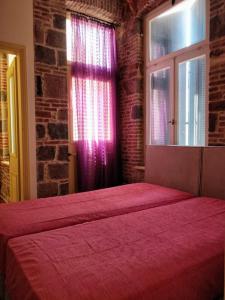ein rotes Bett in einem Zimmer mit Ziegelwand in der Unterkunft Νεοκλασική Κατοικία στο Κέντρο in Mytilini