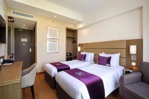 a hotel room with two beds and a desk at Premier Place Surabaya Airport in Sidoarjo