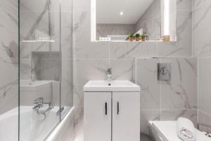 a white bathroom with a sink and a tub and a toilet at Luxurious 2 BR - Apartment - Central Location in London