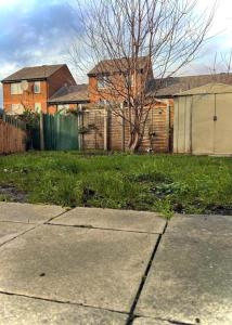 a yard with a house and a tree and a sidewalk at Entire 2 bedroom house in Hackney in London