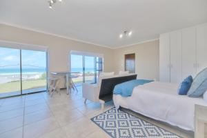 Un dormitorio con una cama, un escritorio y una mesa. en Happy Tides In Struisbaai, en Struisbaai