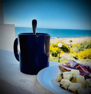 una taza de café azul sentada junto a un plato de comida en Mojacar Casa El Cantal Playa con vistas la Mar, en Mojácar