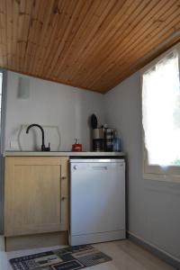 a kitchen with a white dishwasher and a wooden ceiling at Maison grande terrasse 5min plage in La Barre-de-Monts