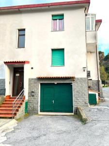 uma casa branca com portas verdes de garagem e escadas em Green House Nonna Angela em Spotorno