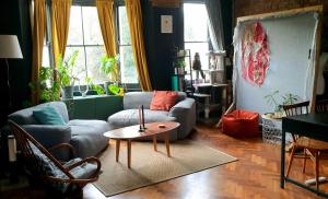 a living room with a couch and a table at Charming bedroom in artist studio in London