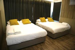 een hotelkamer met 2 bedden met gele kussens bij PoolVillaPattaya next to the sea in Ban Rong Po