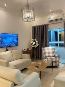 a living room with white furniture and a chandelier at كورنيش عجمان in Ajman 