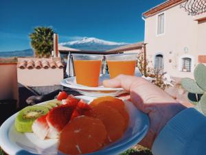 a person holding a plate of fruit and two glasses of juice at Villa Laura Apartment in Giardini Naxos