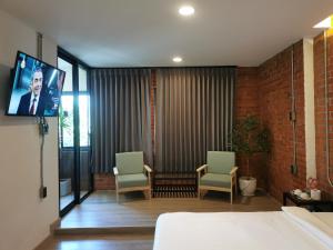 a hotel room with two chairs and a tv at BETONG HELLO GUESTHOUSE in Betong
