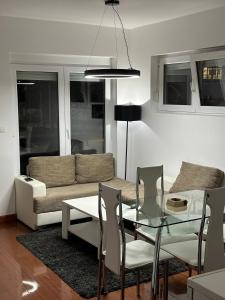 een woonkamer met een glazen tafel en een bank bij Apartman Aurora in Veliko Gradište