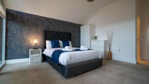 ein Schlafzimmer mit einem großen Bett mit einer Wand mit blauen Akzenten in der Unterkunft Northumberland Luxury Stays - The Galloway in West Chevington