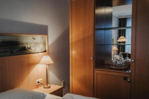 a bedroom with a bed and a lamp and a mirror at Hotel Spiekeroog in Spiekeroog