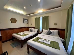 um quarto de hotel com duas camas e uma televisão em Desert Rose Beach Hotel em El Nido