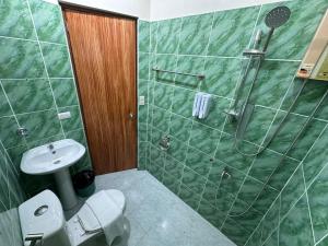 a bathroom with a green tiled shower and a toilet at Desert Rose Beach Hotel in El Nido
