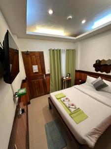 a bedroom with a large bed with a tv on it at Desert Rose Beach Hotel in El Nido