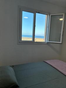 una camera da letto con finestra affacciata sulla spiaggia di Casa Mirtilla a Playa del Burrero
