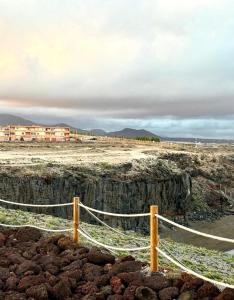 Playa del Burrero的住宿－Casa Mirtilla，沙漠中带有铁丝网的有建筑物的围栏