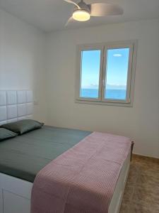 een slaapkamer met een bed, een plafondventilator en 2 ramen bij Casa Mirtilla in Playa del Burrero