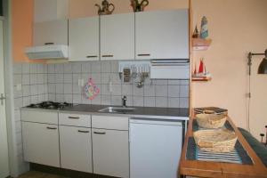 a kitchen with white cabinets and a sink at Heggerank 80* in Nieuwvliet +16 photos