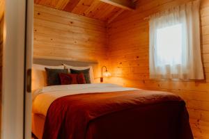 een slaapkamer met een bed in een houten kamer bij Romantisch Wellness Boshuisje met Sauna & Hottub in Meijel